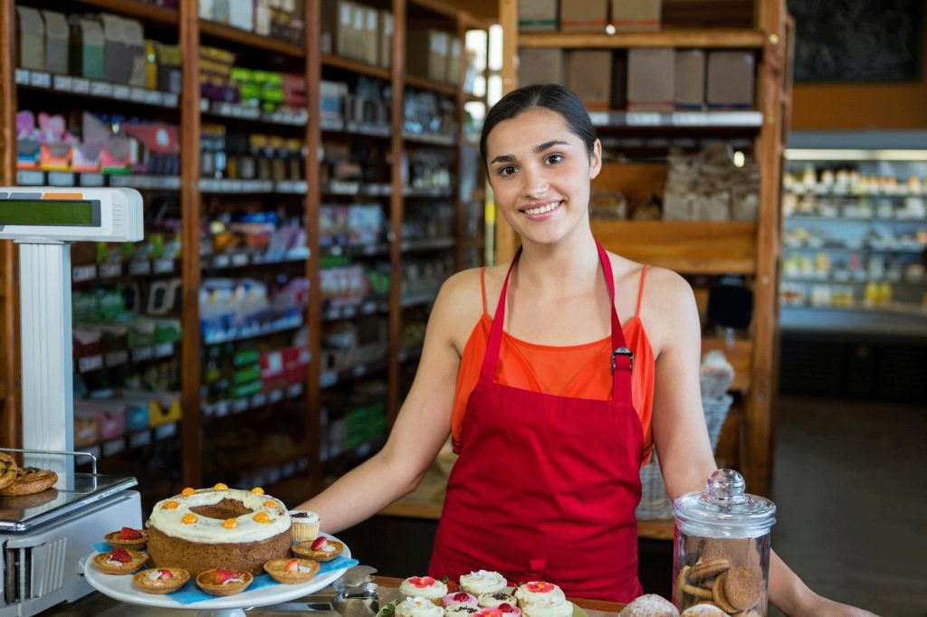 Comerciante sonriente en el mostrador de su local limpio, iluminado y decorado.