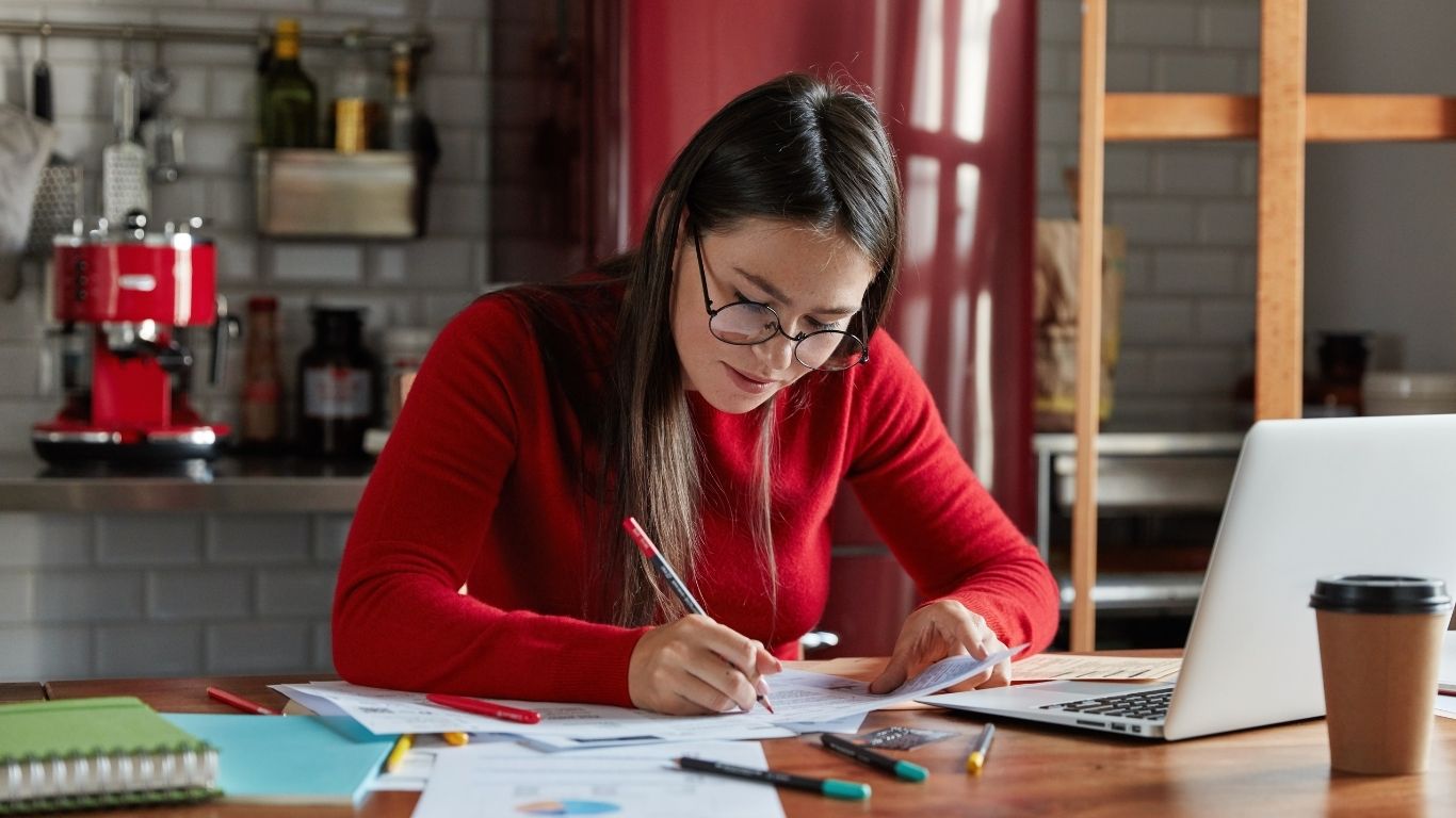 Mujer mexicana organizando en cuaderno las finanzas de su negocio.