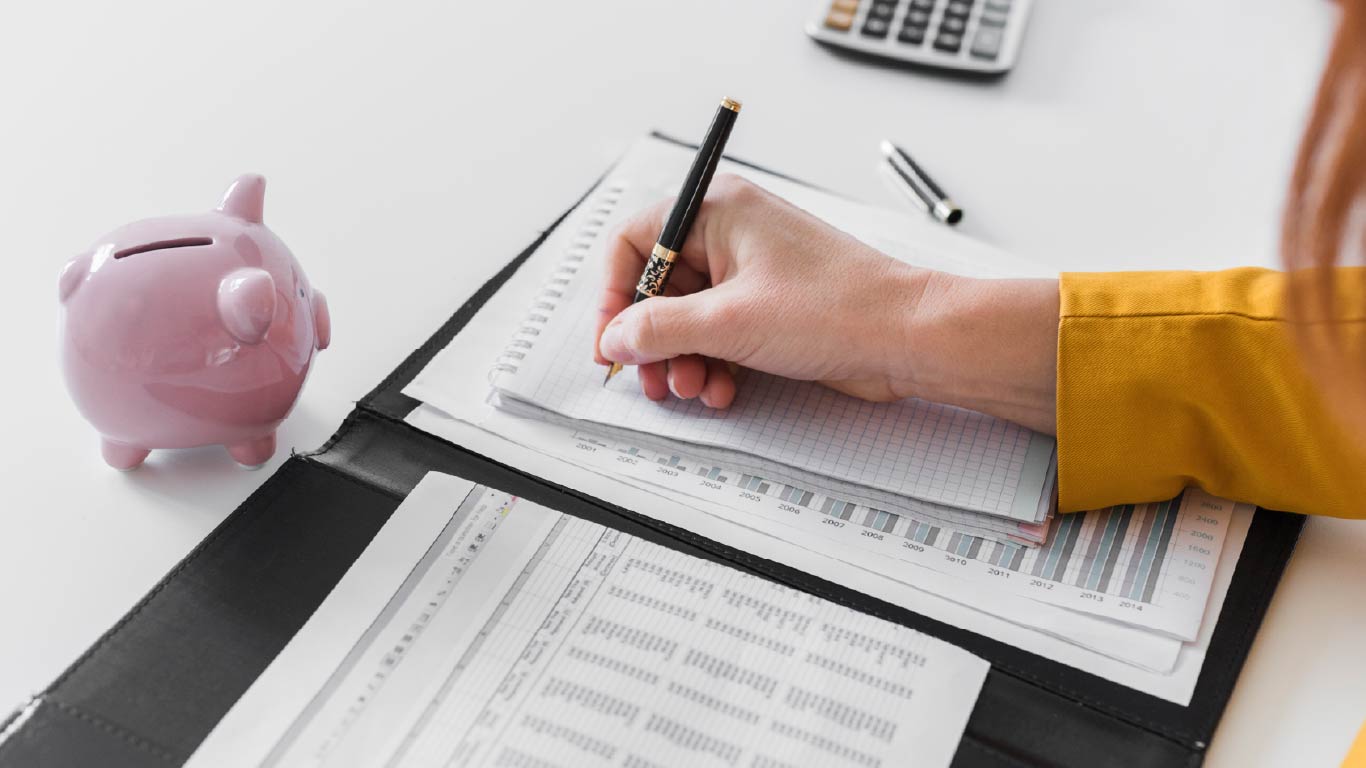 Mujer haciendo anotaciones financieras a mano, reflejando el control, planeación y cuidado de su historial crediticio.
