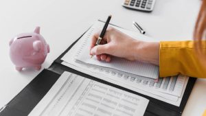 Mujer haciendo anotaciones financieras a mano, reflejando el control, planeación y cuidado de su historial crediticio.