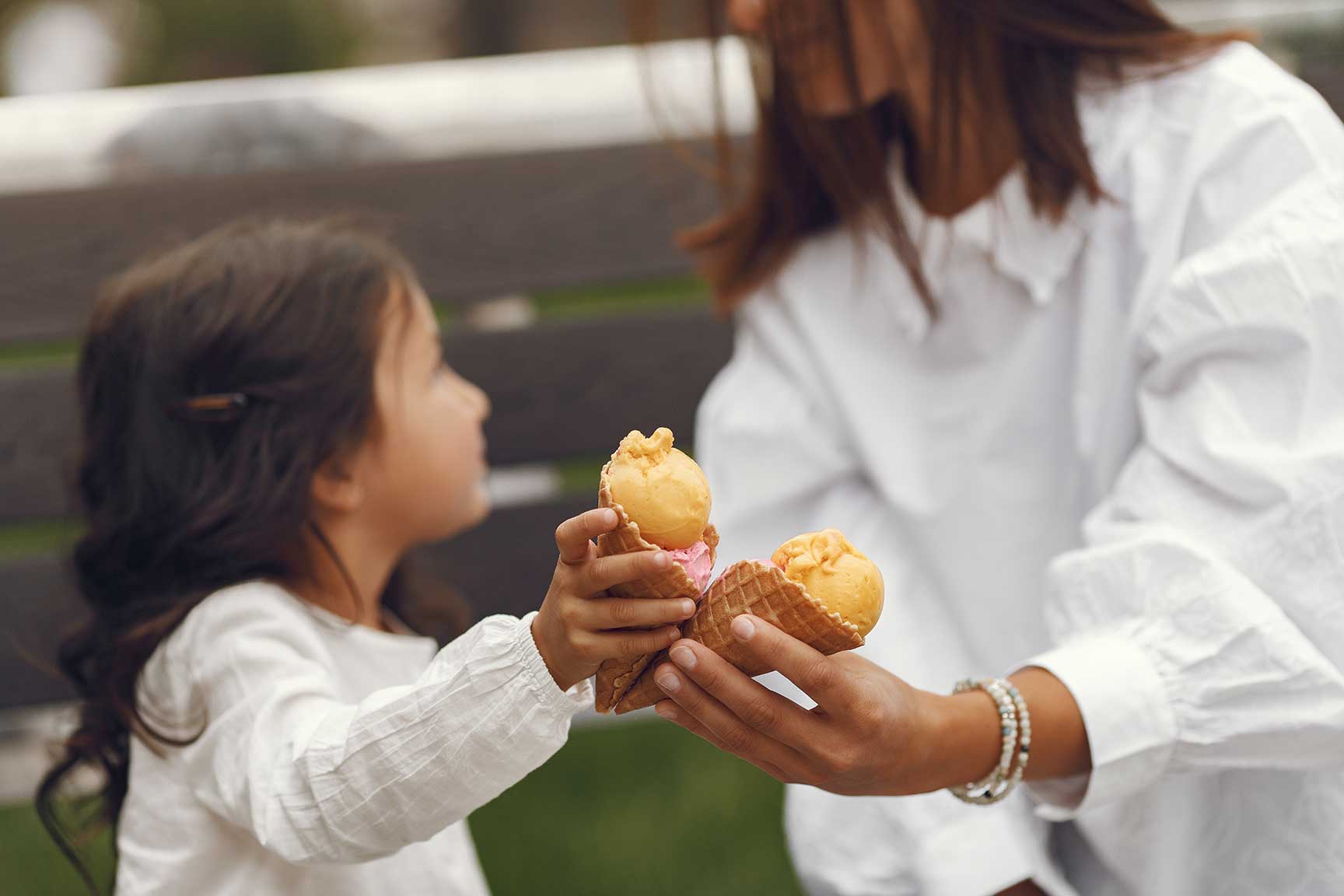 Microempresaria mexicana compartiendo un helado de cono con su hija durante sus vacaciones de verano.